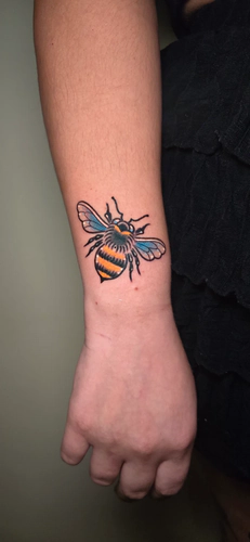 Colorful neo traditional bumblebee wrist tattoo by Chyloe at Golden Tarot Ink Club