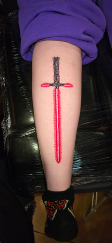 Red crossguard lightsaber tattoo on the lower leg by Chyloe at Golden Tarot Ink Club